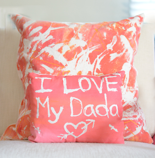 Two coral colored glue-resist throw pillows with "I Love My Dada" and heart designs