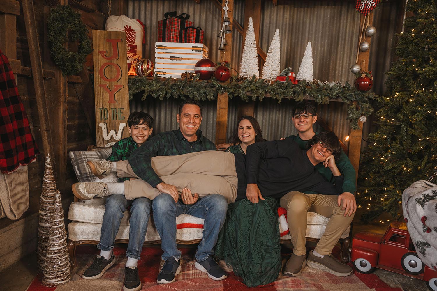 Family sitting on a couch in a Christmas themed room.