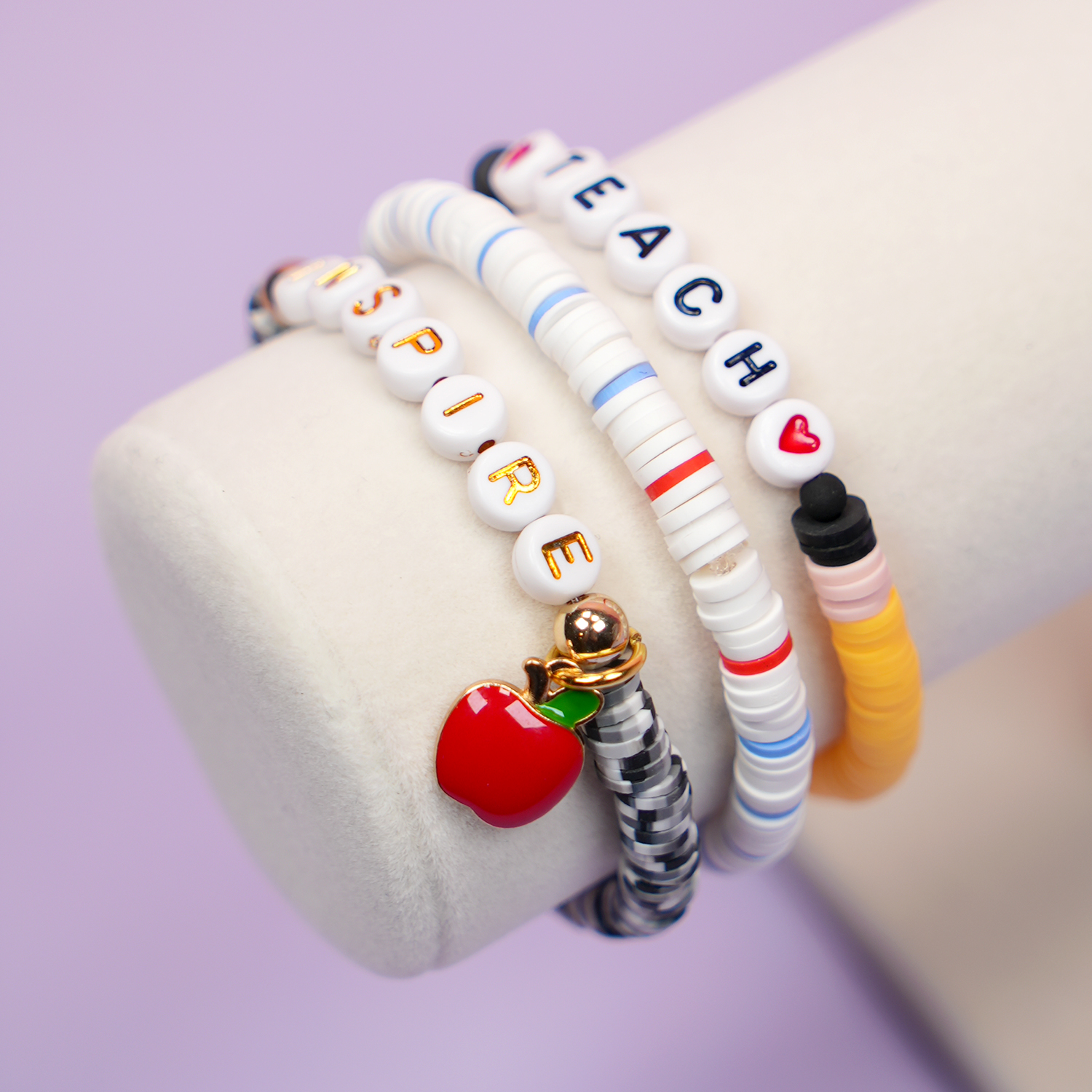 Close up of beaded teacher bracelets made to look like a pencil, notebook paper, and a composition book