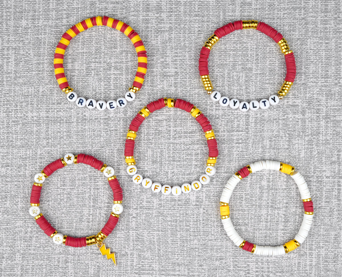 Five beaded red, yellow, and gold bracelets on a grey background with Gryffindor Hogwarts house traits in alphabet letters