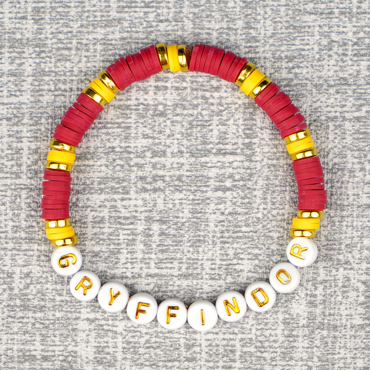 red, yellow, and gold beaded bracelet with "Gryffindor" alphabet beads on grey background