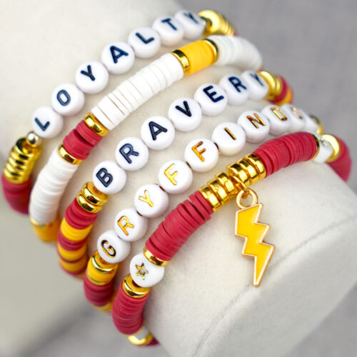 Close-up of five beaded Gryffindor red and gold Harry Potter bracelets with words "Gryffindor, Loyalty, and Bravery" with lighting bolt charm