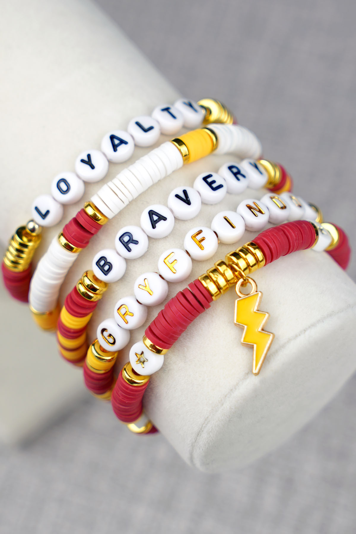 Close-up of five beaded Gryffindor red and gold Harry Potter bracelets with words "Gryffindor, Loyalty, and Bravery" with lighting bolt charm