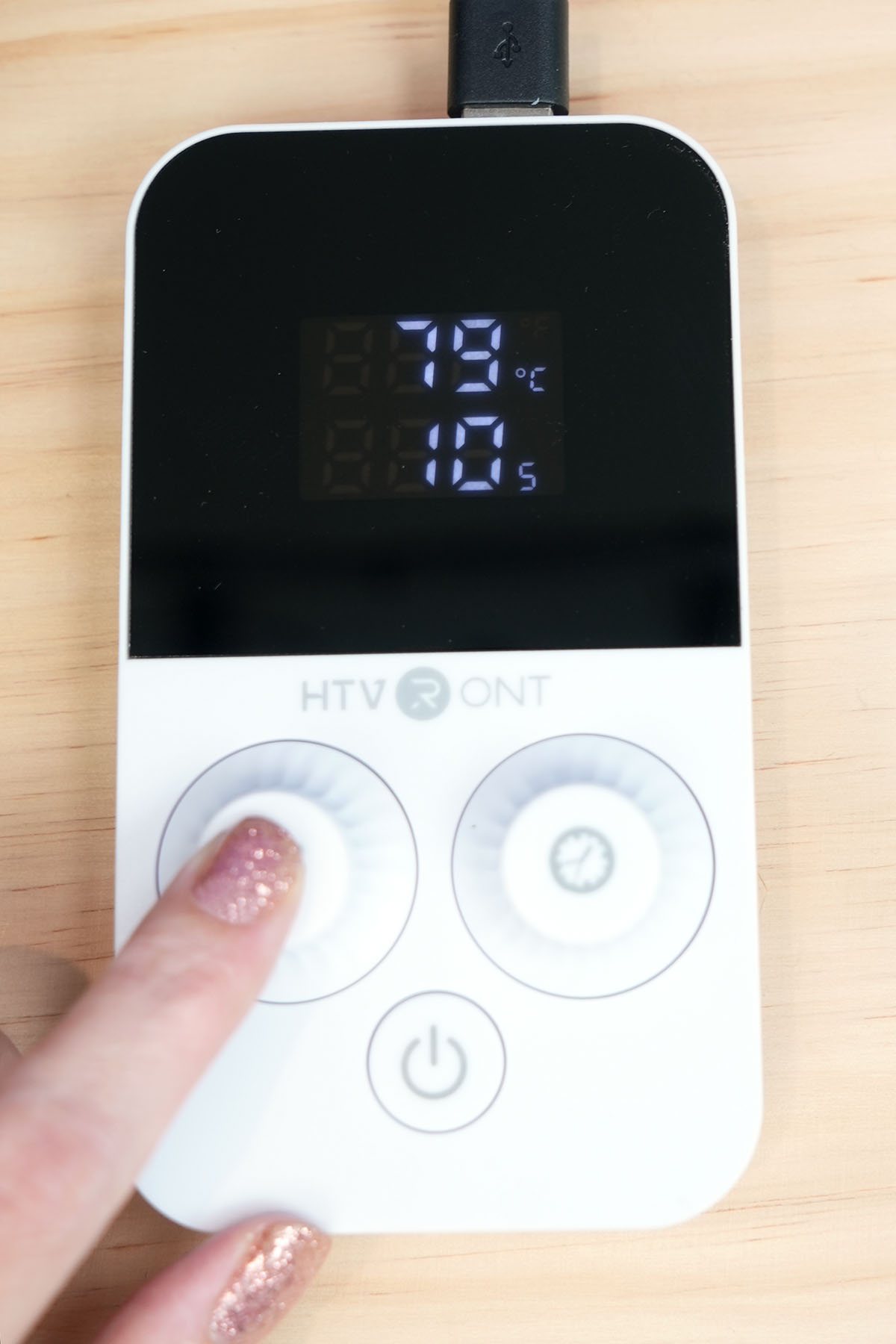 Close up of hand adjusting temperature settings on control dial