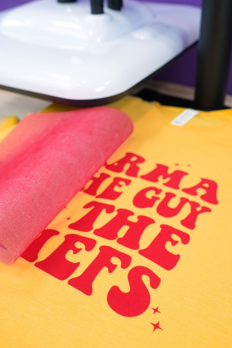 Close-up of red flocked velvet heat transfer vinyl design detail on gold shirt