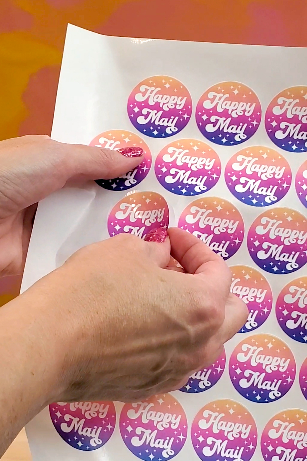 Close up of hands peeling a sticker off of a larger kiss cut sticker sheet