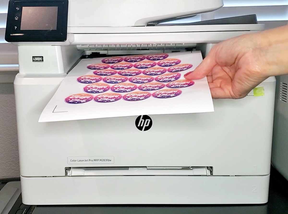 Close up of hand removing a sheet of printed labels off of an HP  laser printer