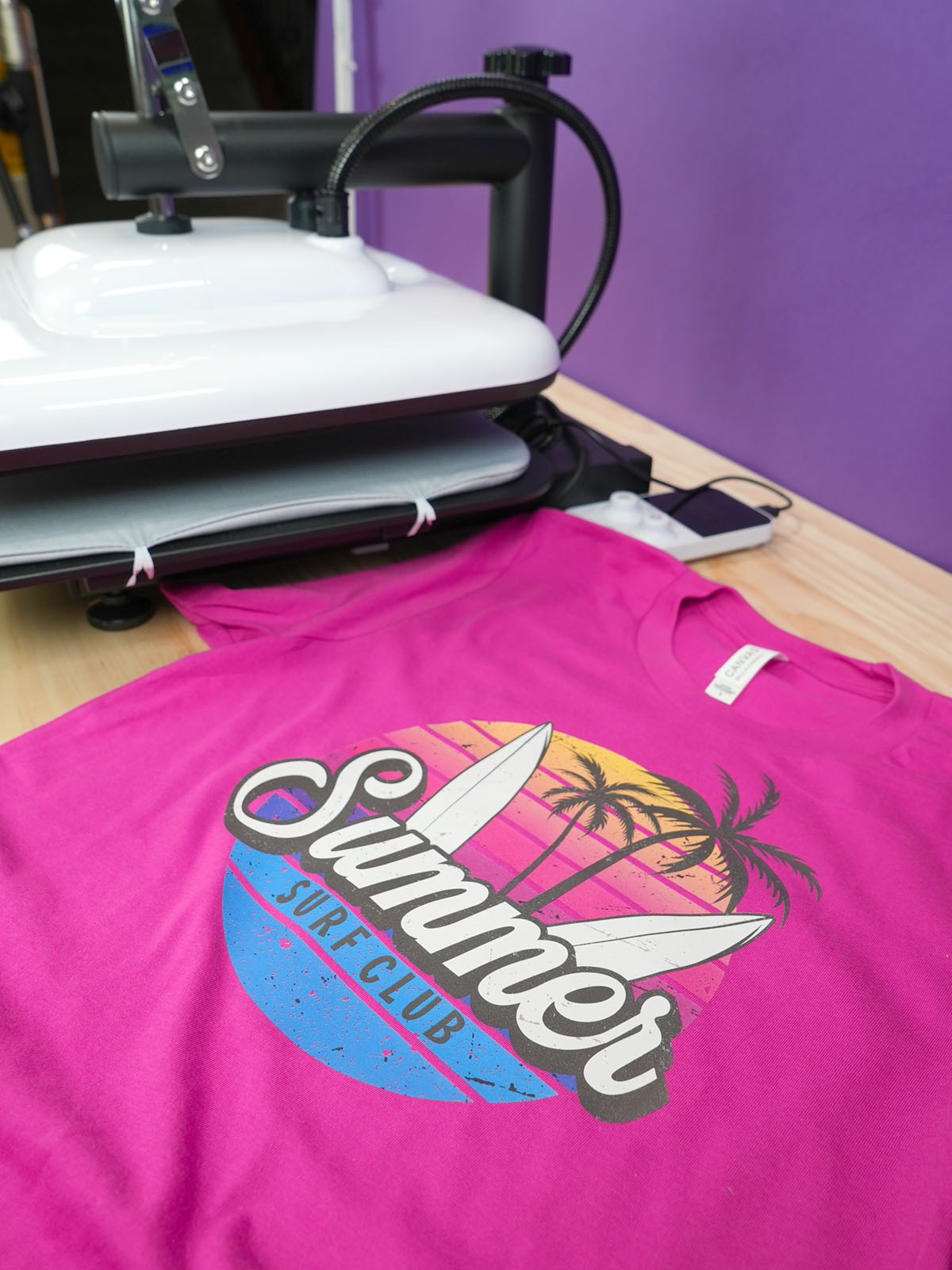 Side angle view of finished hot pink "Summer Surf Club" shirt next to the HTVRONT Manual Heat Press Machine