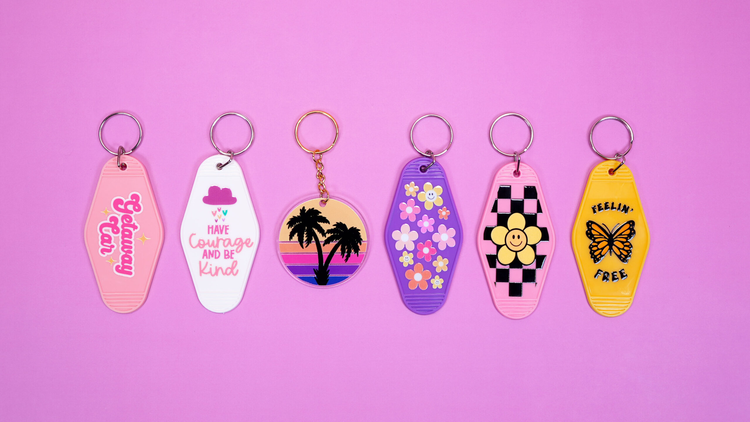 Six colorful keychains with UV DTF patterns and designs on a light purple background