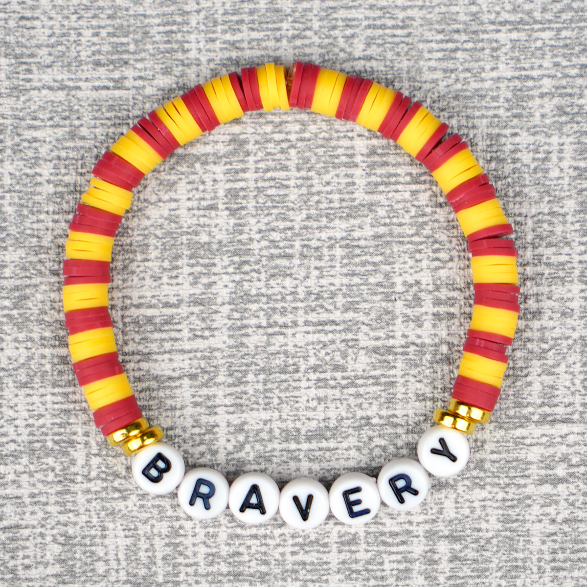 red and yellow beaded bracelet with "Bravery" alphabet beads on grey background