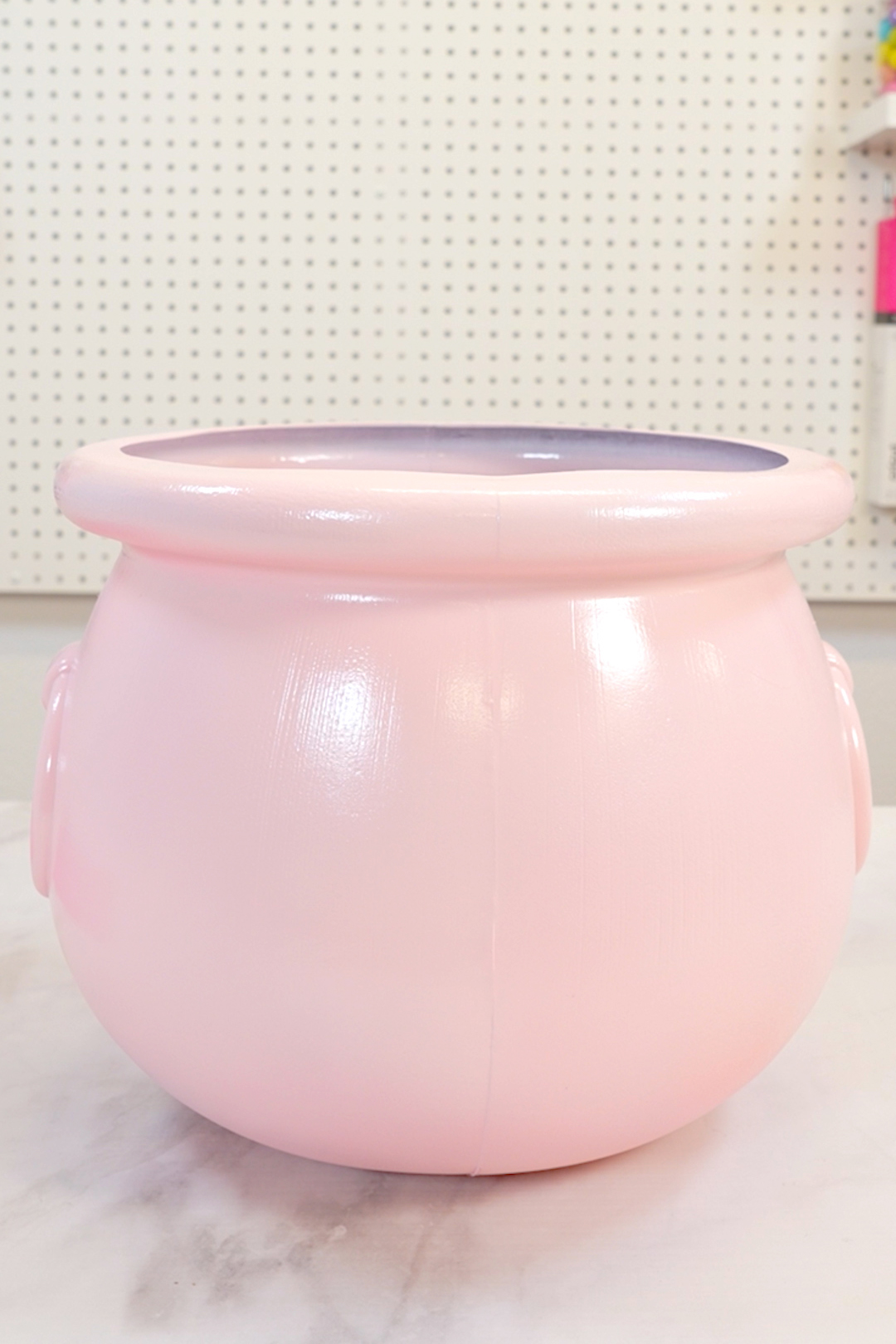 Pink painted plastic cauldron sitting on table top with white background